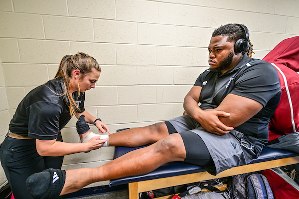 Athletic Trainer helping football player prior to game