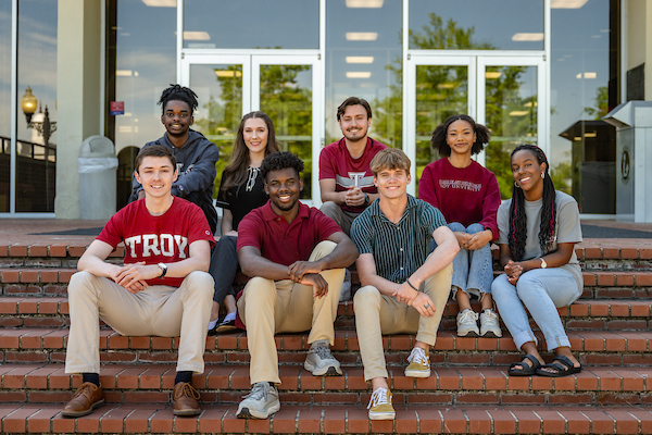 TROY students sitting on the steps in front of the library.