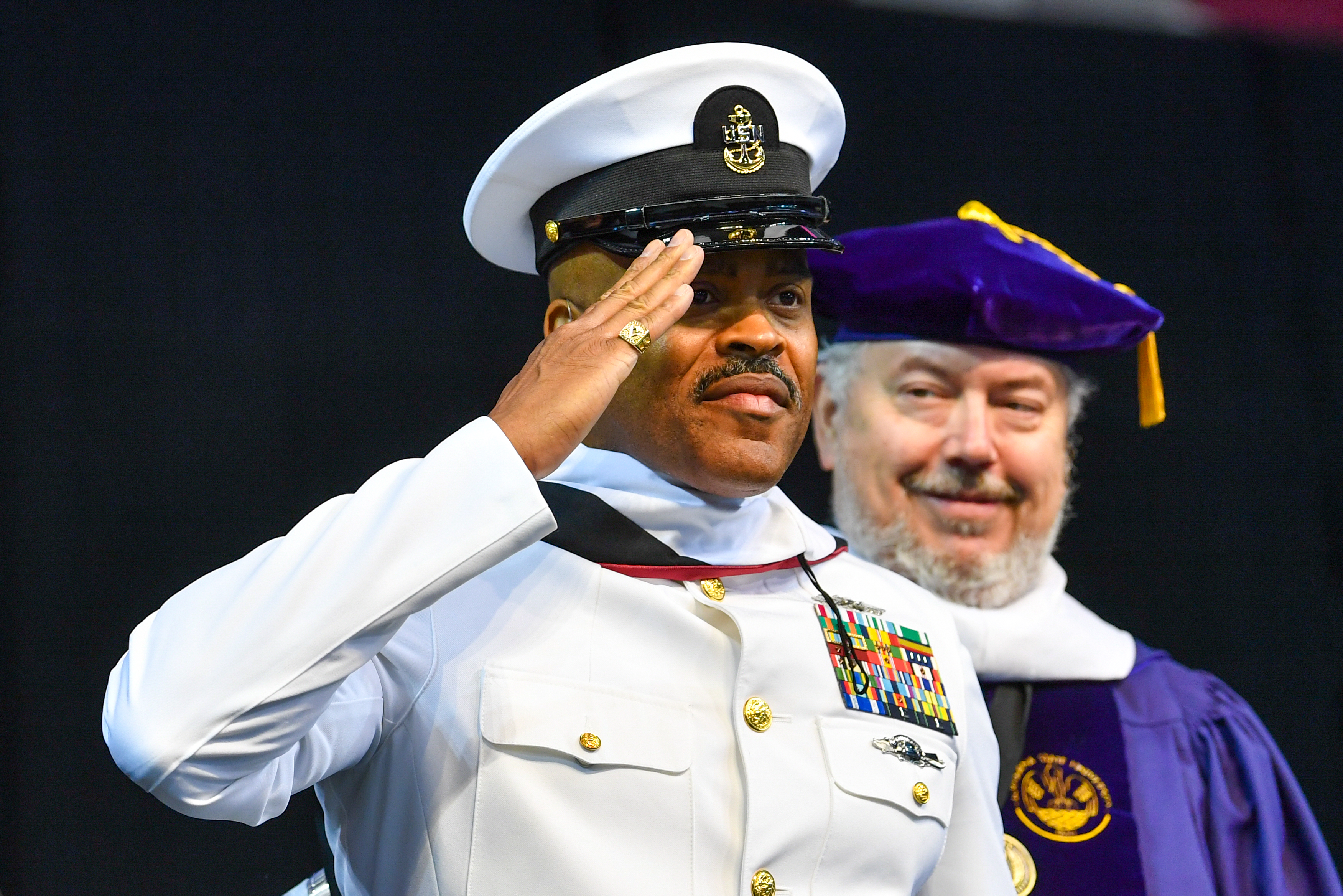 Military student saluting the crowd during commencement at Troy University.
