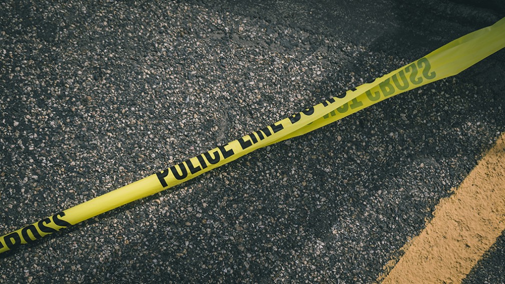 Police Line yellow tape across paved road