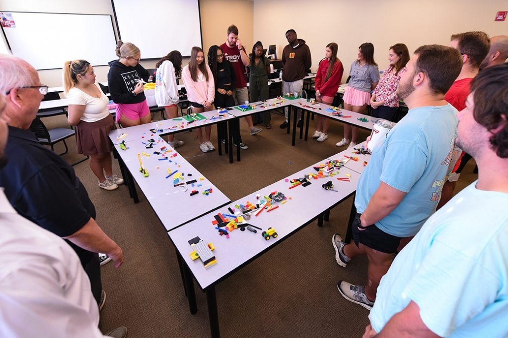 A group of students standing by a table and LEGO blocks.  