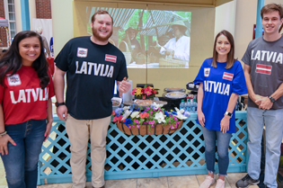 Four International Troy University Business students standing in front of an exhibit.