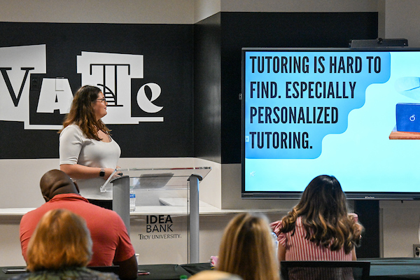 high school girl presenting her pitch project in a room wiuth judges