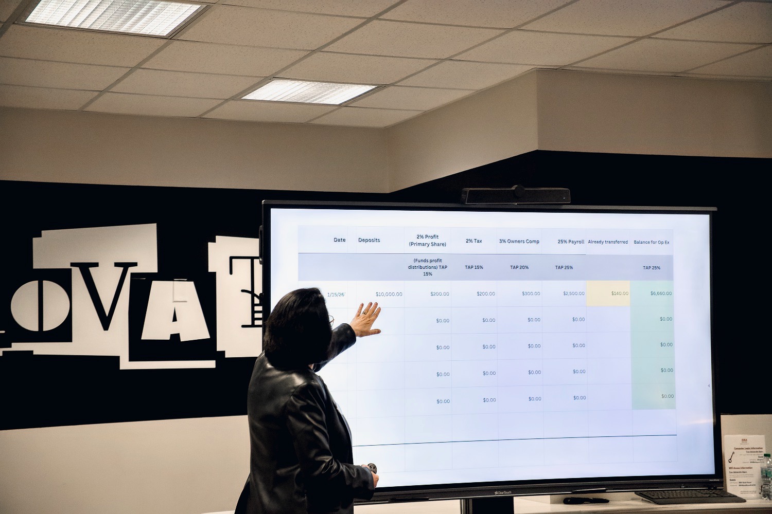 A woman presenting in front of a screen inside the main room of the IDEA Bank.