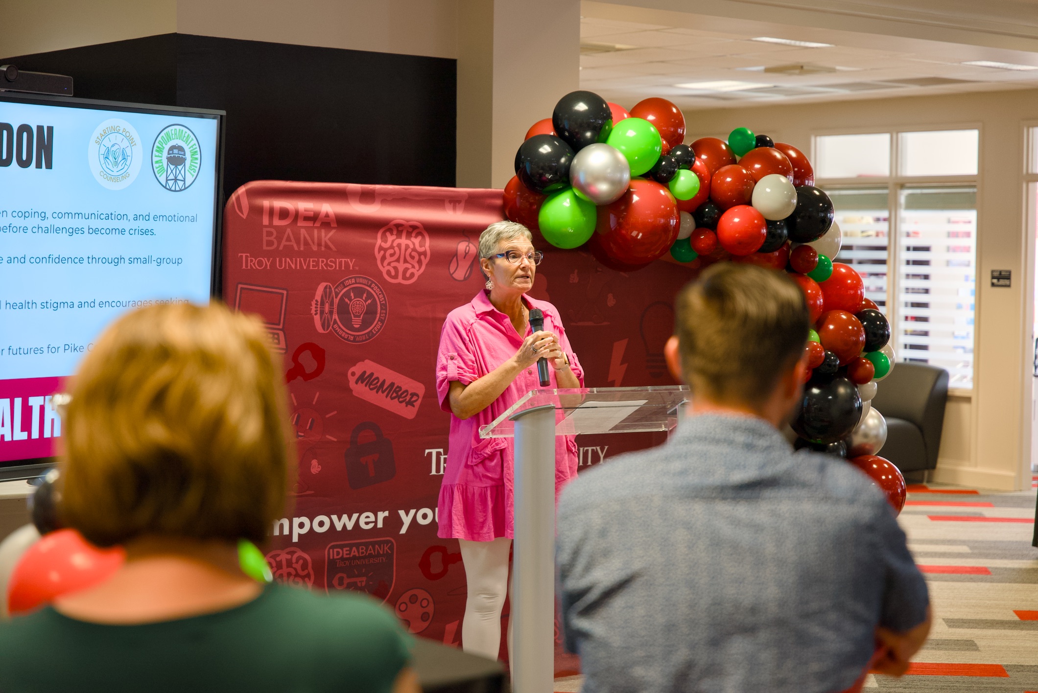 A woman presenting in front of a screen inside the main room of the IDEA Bank.