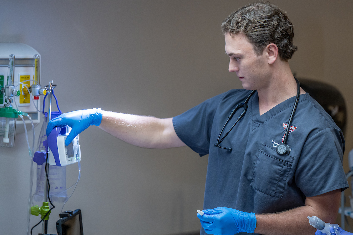 Nursing male student using equipment in lab.