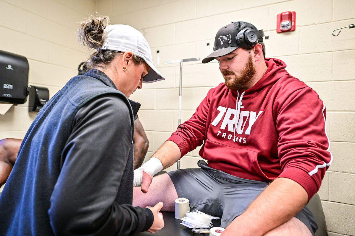 Troy University Athletic Trainer student helping Troy Trojan Football player before the game.