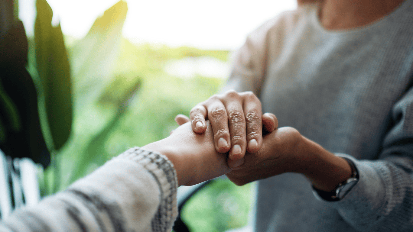 two individuals holding hands with a green, plan-life background. 
