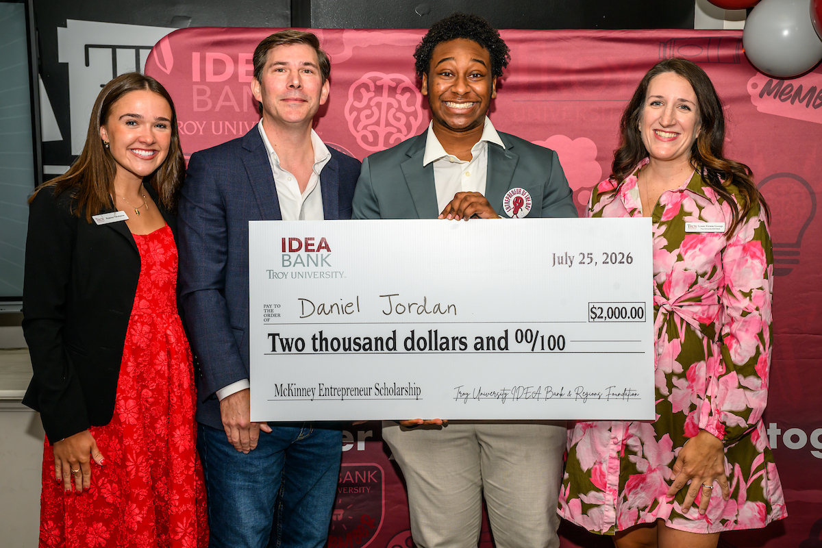 High school student holding big check for $2,000 scholarship to troy