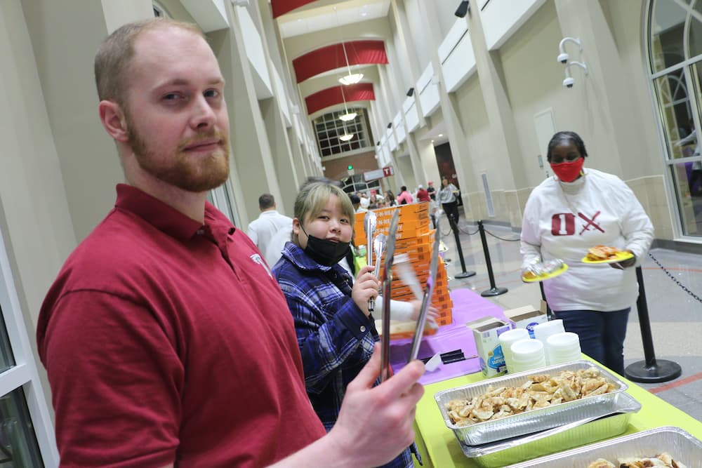 Associate Director Austin Deal and Assistant Duolinna smiling for the camera in the food line