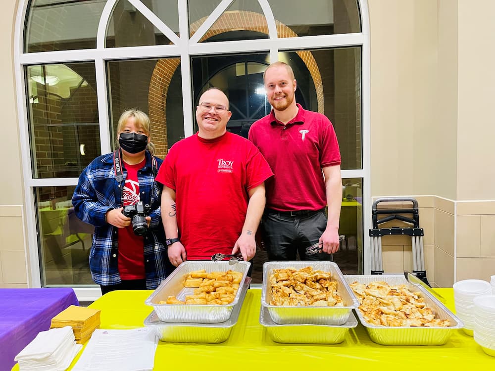 Group photo of Associate Director Austin Deal and Assistants Jon Garrett and Duolinna at the food line