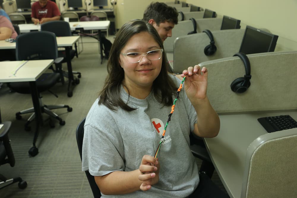 A Troy student proudly showing her finished bracelet