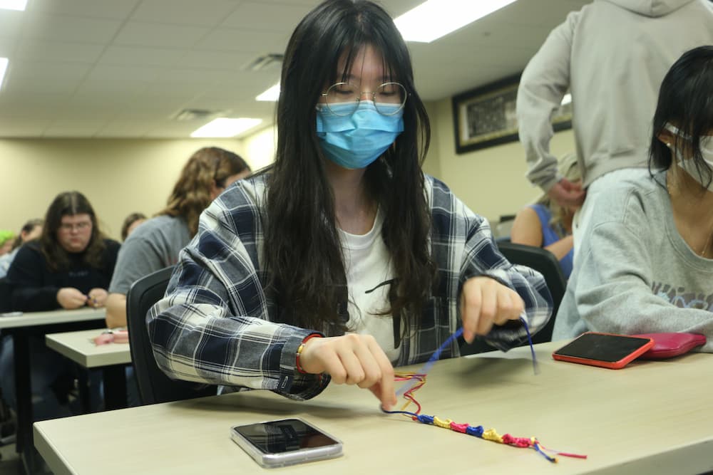 Troy student crafting her bracelet