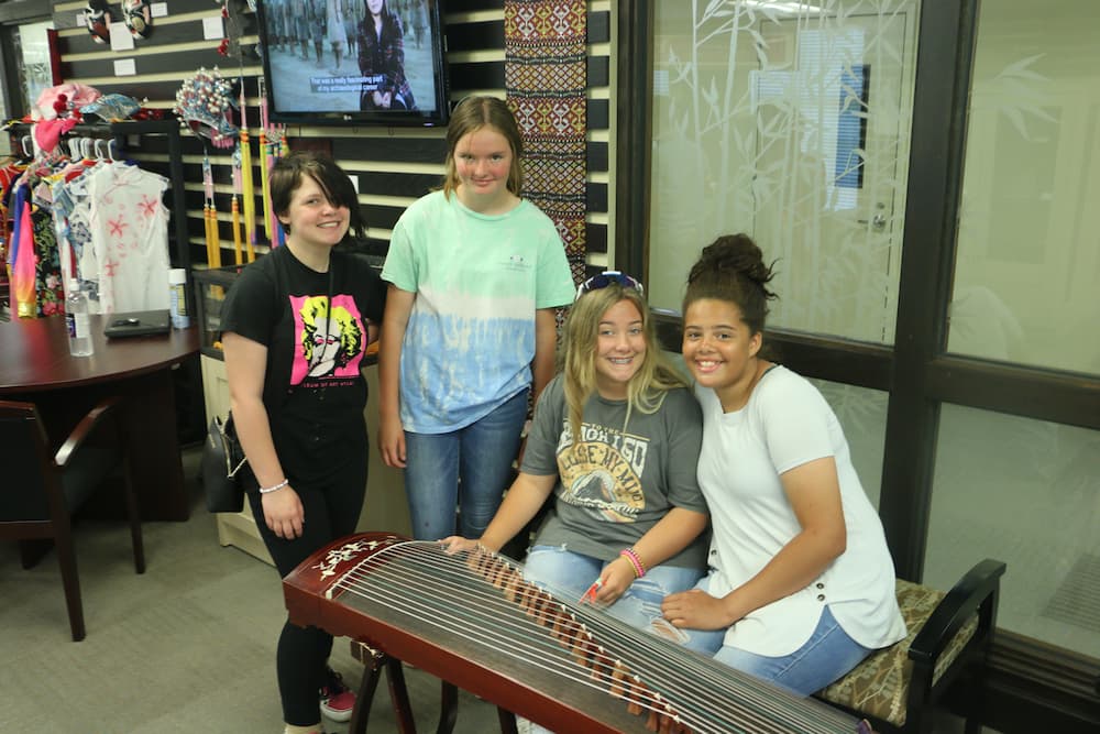 Four students playing the Chinese guzheng instrument