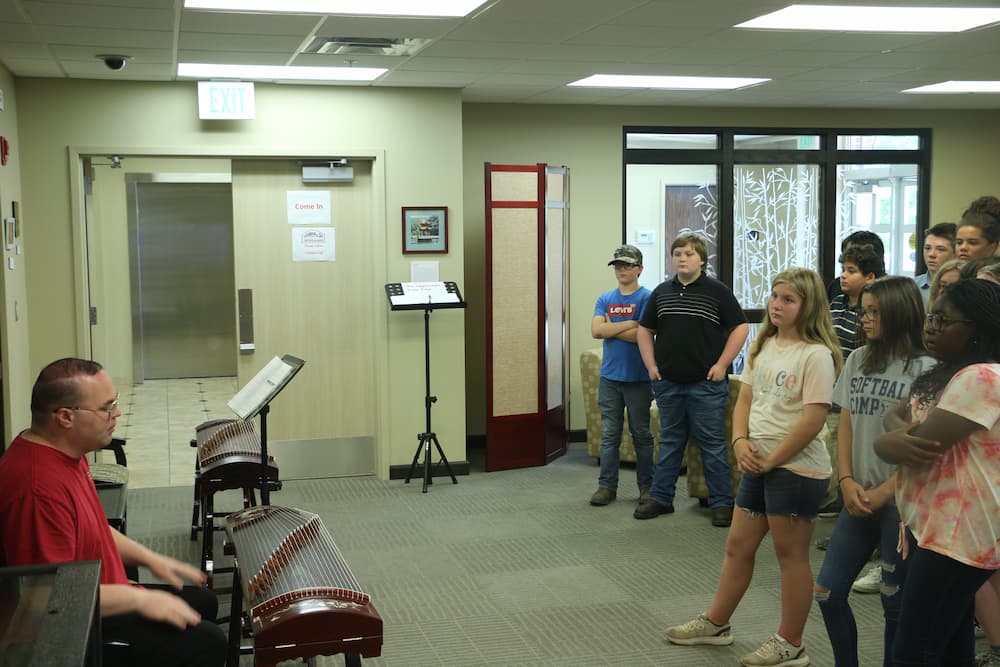 Assistant Jon Garrett talking to the students about the history of the Chinese guzheng instrument