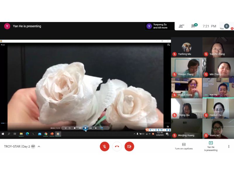 He Yan holds the finished rose for the participants to see while they finish up their own crafts.