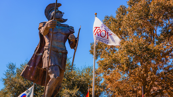 Profile view of the Trojan Statue and Troy University flag on the Dothan Campus