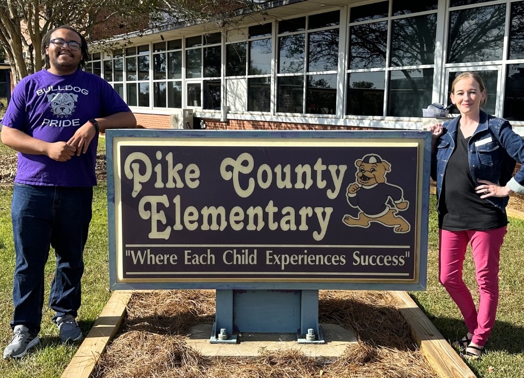 Deven Reese and a colleague standing beside the Pike Country Elementary School sign. 
