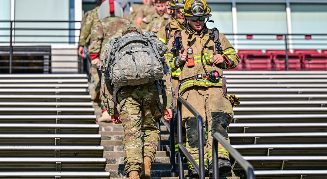 Firemen and Military members walking the stadium stairs in remembrance of 9/11.