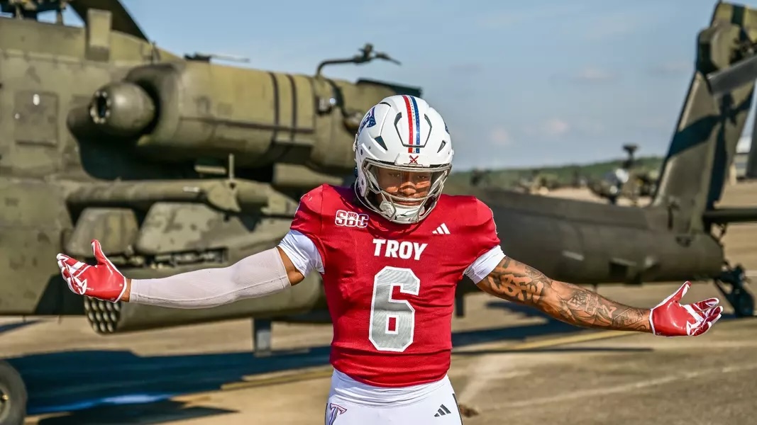 TROY Football player posing in front of a military helicopter. 