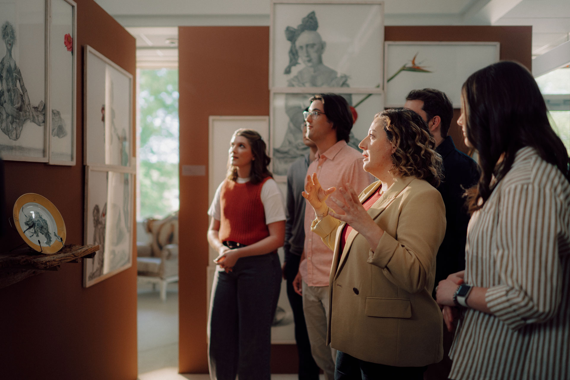 An art and design professor discusses artwork with TROY students in the International Arts Center on the Troy Campus.