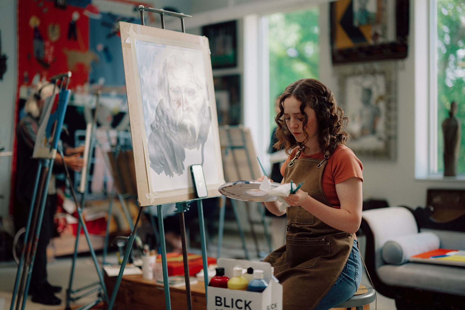 Art student painting on an easel in an art studio. 