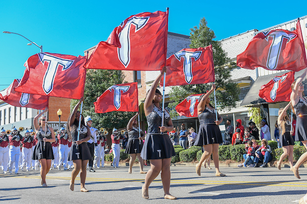 Color Guard Students walking through downtown with TROY flags for the Homecoming Parade