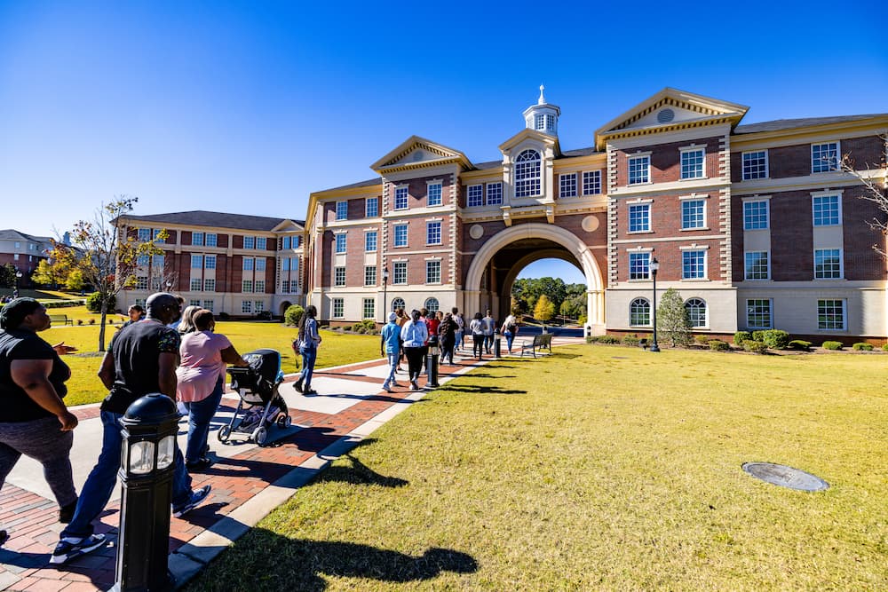 Campus tour guide leading a group tour into Rushing Hall on Troy University's campus.