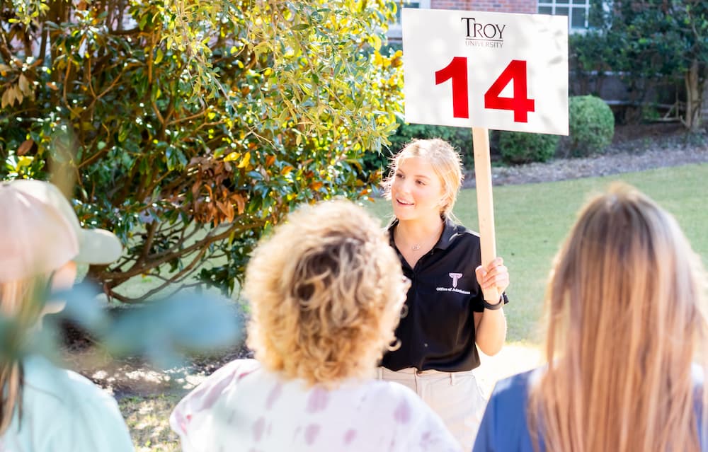 Campus tour guide leading a group tour of Troy University's campus on Trojan Day.